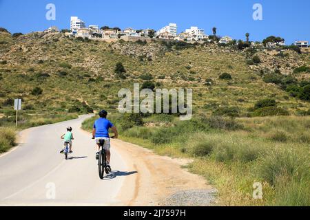 Santa Pola, Alicante, Spanien - 6. Mai 2022: Radfahrer fahren entlang der Straße, die an die kleinen Strände des Leuchtturms in Santa Pola, Alicante grenzt Stockfoto