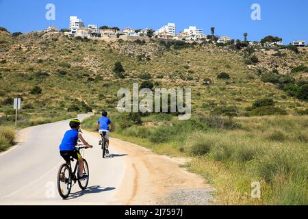 Santa Pola, Alicante, Spanien - 6. Mai 2022: Radfahrer fahren entlang der Straße, die an die kleinen Strände des Leuchtturms in Santa Pola, Alicante grenzt Stockfoto