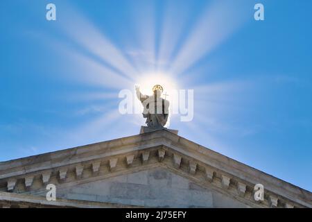 Statue von Jesus Christus umgeben von Sonnenstrahlen gegen klaren blauen Himmel Stockfoto