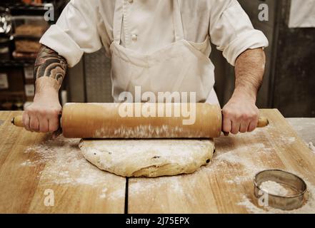 Ein Bäcker rollt Teig in einer Bäckerei Stockfoto