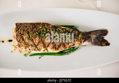 Gegrillter Fisch mit Herbes de Provence und frisch geschnittenem Schnittlauch Stockfoto