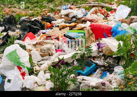 Unschärfe riesige Mülldeponie. Konzept der Ökologie. Große Müllhaufen auf Natur grünen Gras Hintergrund, globale Erwärmung. Nahaufnahme. Verschmutzung. Aus Stockfoto