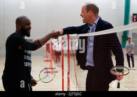 Der Duke of Cambridge schüttelt sich die Hände mit Simeon Mosquito, während er Badminton spielt, während er Sports Key im Doug Ellis Sports Centre in Birmingham besucht, das Aktivitäten für die Gemeinschaft zur Verbesserung des Wohlbefindens, des Zusammenhalts und der Lebenschancen benachteiligter Menschen bietet. Bilddatum: Freitag, 6. Mai 2022. Stockfoto