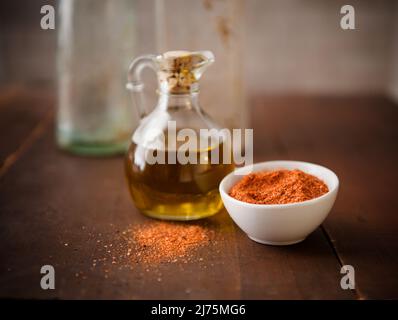 Eine kleine Flasche Olivenöl und eine Schüssel mit Gewürzen Stockfoto