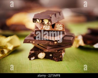 Stapel von verschiedenen Schokoladentafeln auf Grün; Wrapper Stockfoto