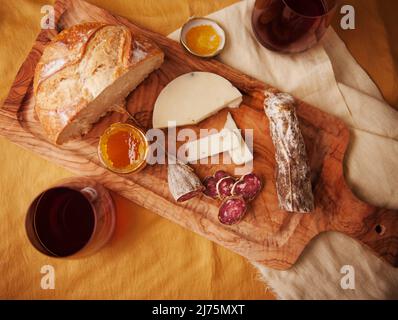 Salami, Käse, Brot und Marmelade auf einem Holzbrett Stockfoto