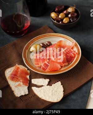 Spanischer Jamon Ibérico mit Crackern, Oliven und Rotwein Stockfoto