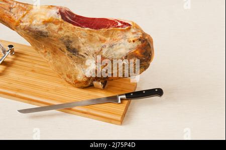 Ein ganzer spanischer Jamon Ibérico auf einem Schneidebrett, das fertig geschnitten werden kann Stockfoto