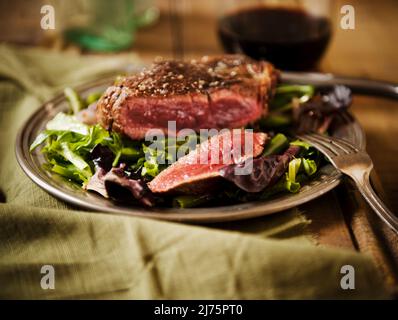 Sliced Grass Fed Sirloin Steak auf einem Bett mit Wein Stockfoto