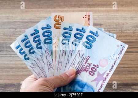 Eine Hand mit türkischen hundertfünfzig Banknoten auf Holzoberfläche Stockfoto