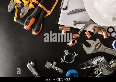 Konzept der Sanitär-technischen Service und Revisionen mit Notizblock und Werkzeuge und Sanitär-Material auf schwarzem Tisch. Draufsicht. Horizontale Kompo Stockfoto