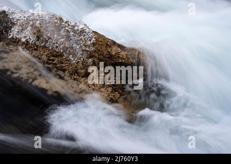 Klares Eis im Winter auf einem Stein in der Strömung am Rissbach im sogenannten eng in Tirol im Karwendelgebirge mit klarem Wasser und starker Strömung Stockfoto