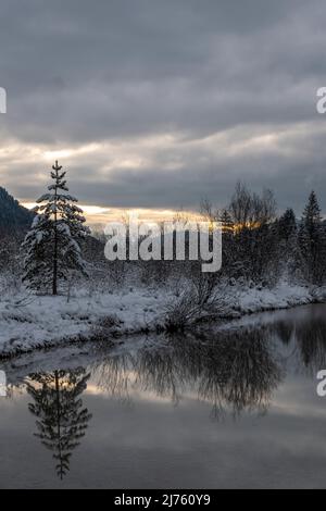 Dichte Wolken bei Sonnenuntergang in den Isarwiesen bei Wallgau im Karwendel, mit dem Bachbett / Flusslauf im Vordergrund Stockfoto