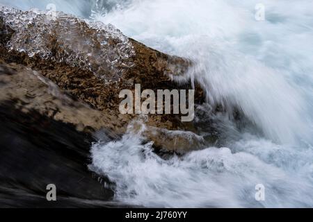 Klares Eis im Winter auf einem Stein in der Strömung am Rissbach im sogenannten eng in Tirol im Karwendelgebirge mit klarem Wasser und starker Strömung Stockfoto