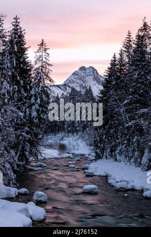 Der Rißbach im sogenannten eng, das schmale Tal zum Ahornboden in Tirol im Winter mit viel Schnee, bei Sonnenuntergang mit rosafarbenen Wolken und dem majestätischen Berggipfel Stockfoto