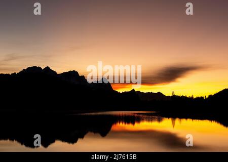 Das Wettersteingebirge mit Zugspitze spiegelte sich zusammen mit einer Wolke bei Sonnenuntergang in Geroldsee/ Wagenbrüchsee Stockfoto