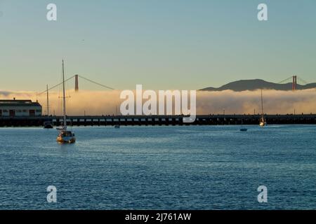 Segelboot in der Nähe des städtischen Pier mit der Fog Laden Golden Gate Bridge in the Distance, San Francisco, Kalifornien, USA Stockfoto