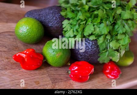 Frische rote Chilischoten aus Scotch Bonnet mit Limetten-Koriander und Avocado-Zutaten zur Herstellung von Guacamole Stockfoto