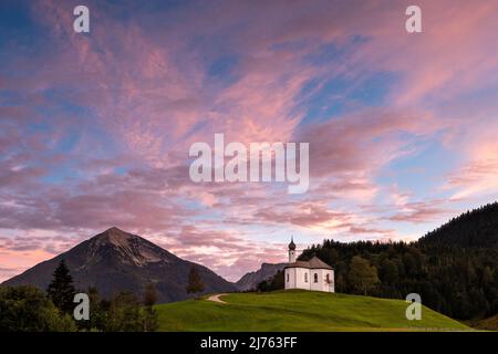 Das kleine Annakircherl, eine kleine Kapelle auf einem Hügel in Achenkirch am Ende des Karwendels in den Alpen, Tirol nach Sonnenuntergang. Lila und blaue Töne dominieren den Abendhimmel. Im Hintergrund die Berge. Stockfoto