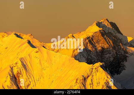 Goldenes Licht bei Sonnenaufgang lässt die Zugspitze und den Grat der Hochblassen oberhalb von Garmisch-Partenkirchen in den deutschen Alpen goldgelb leuchten. Blick von der Westkarwendelspitze. Stockfoto