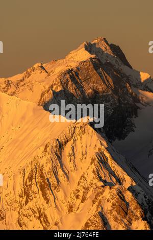 Goldenes Licht bei Sonnenaufgang lässt die Zugspitze und den Grat der Hochblassen oberhalb von Garmisch-Partenkirchen in den deutschen Alpen goldgelb leuchten. Blick von der Westkarwendelspitze. Stockfoto