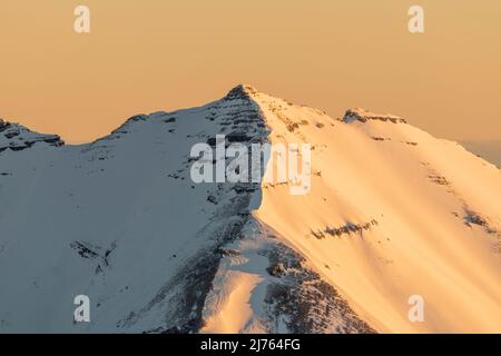 Die Soiernspitze erstrahlt bei Sonnenaufgang in goldenem, orangenen Licht. Aufgenommen im Winter mit Schnee und Eis von der westlichen Karwendelspitze oberhalb von Mittenwald. Stockfoto