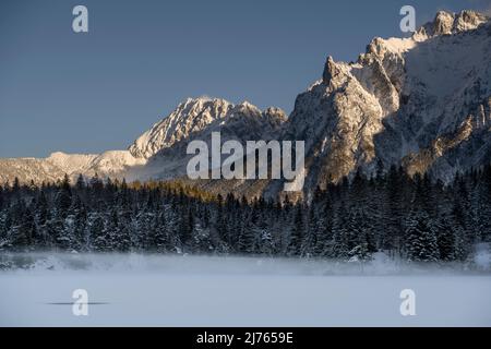 Der gefrorene lautersee mit Bodennebel und Schnee im Winter. Im Hintergrund das Karwendelgebirge mit der Viererspitze und dem Wörner Stockfoto