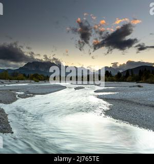 Der Wasserlauf der Isar bei Wallgau kurz nach Sonnenuntergang als Langzeitbelichtung. Im Hintergrund das Wettersteingebirge und die Zugspitze, umhüllt von dichten Wolken. Stockfoto