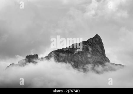 Die Grabenkarspitze im Karwendel, der Naturpark Karwendel in Tirol, umhüllt von dichten Wolken und Nebel mit sichtbarem Gipfelkreuz Stockfoto