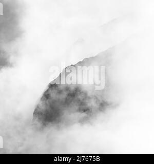 Felsen hängen im Nebel. Die Ränder und Flanken des Gamsjochs im Karwendel über dem großen Ahornboden im Engstal in Tirol. Harte Bergschemata in den Bergen der Alpen in schwarz-weiß Stockfoto