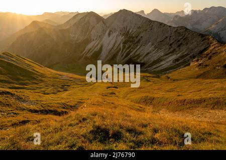 Sonnenstrahlen am frühen Morgen auf dem Schönalmjoch im Karwendel mit Blick den Grat hinunter in Richtung Fleischbank. Aufgenommen im Karwendel bei Hinterriss in den Tiroler Alpen, Österreich. Stockfoto