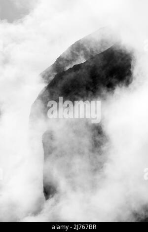 Felsen hängen im Nebel. Die Ränder und Flanken des Gamsjochs im Karwendel über dem großen Ahornboden im Engstal in Tirol. Harte Bergschemata in den Bergen der Alpen in schwarz-weiß Stockfoto