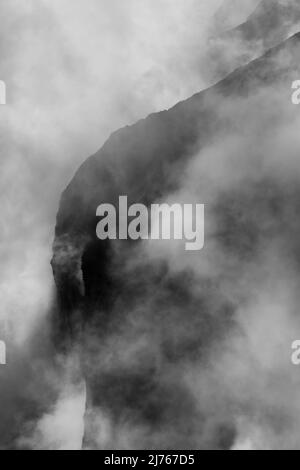 Felsen hängen im Nebel. Die Ränder und Flanken des Gamsjochs im Karwendel über dem großen Ahornboden im Engstal in Tirol. Harte Bergschemata in den Bergen der Alpen in schwarz-weiß Stockfoto