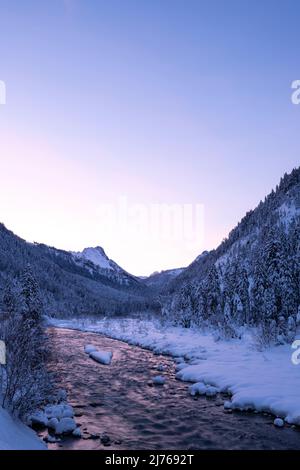 Sonnenuntergang am Rissbach im Karwendel im sogenannten eng beim Ahornboden in Tirol / Österreich im Winter mit Schnee. Der Strom spiegelt die Farben des Sonnenuntergangs wider. Stockfoto