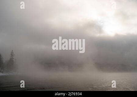 Düstere Nebelatmosphäre mit Sonne, die im Winter am Walchensee durchscheint Stockfoto