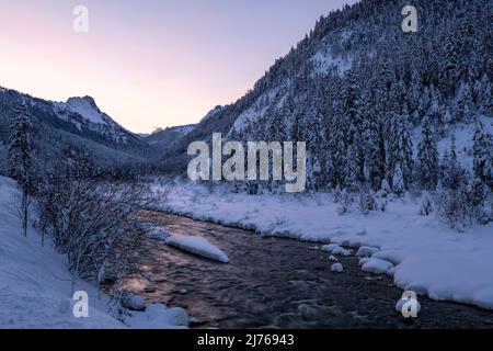 Sonnenuntergang am Rissbach im Karwendel im sogenannten eng beim Ahornboden in Tirol / Österreich im Winter mit Schnee. Der Strom spiegelt die Farben des Sonnenuntergangs wider. Stockfoto