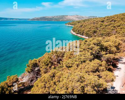 Von oben können Sie das Meer und einen Teil des Gebiets von Seget Vranjica in Kroatien sehen. Im Vordergrund viel Wald. Stockfoto