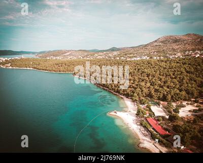 Von oben können Sie das Meer und einen Teil des Gebiets von Seget Vranjica in Kroatien sehen. Im Vordergrund viel Wald. Stockfoto