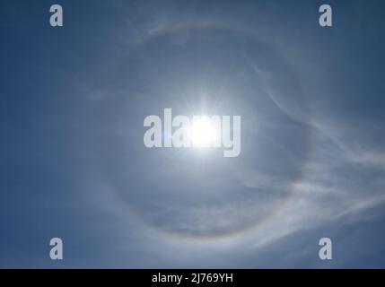 Optisches Phänomen, das als 22-Grad-Halo um die Sonne bezeichnet wird. Eiskristalle in der Atmosphäre brechen Licht und erzeugen den Halo. Stockfoto