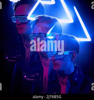 Serious junge Cyber-Mann in Neon-Brille reflektiert in 3D-Effekt, Neonlicht Stockfoto