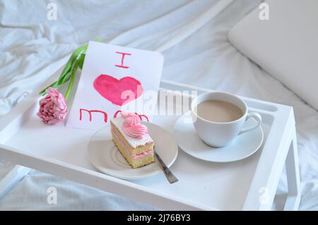 Muttertag, Liebe für Mutter. Morgen mit Sorge für Mama. Ein Tablett mit Kaffee und Kuchen auf dem Bett. Postkarte geschrieben von einem Kind Tochter oder Sohn Ich liebe Mutter PR Stockfoto