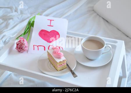 Muttertag, Liebe für Mutter. Morgen mit Sorge für Mama. Ein Tablett mit Kaffee und Kuchen auf dem Bett. Postkarte geschrieben von einem Kind Tochter oder Sohn Ich liebe Mutter PR Stockfoto