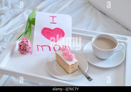 Muttertag, Liebe für Mutter. Morgen mit Sorge für Mama. Ein Tablett mit Kaffee und Kuchen auf dem Bett. Postkarte geschrieben von einem Kind Tochter oder Sohn Ich liebe Mutter PR Stockfoto