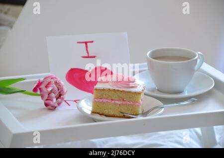 Muttertag, Liebe für Mutter. Morgen mit Sorge für Mama. Ein Tablett mit Kaffee und Kuchen auf dem Bett. Postkarte geschrieben von einem Kind Tochter oder Sohn Ich liebe Mutter PR Stockfoto