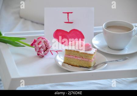 Muttertag, Liebe für Mutter. Morgen mit Sorge für Mama. Ein Tablett mit Kaffee und Kuchen auf dem Bett. Postkarte geschrieben von einem Kind Tochter oder Sohn Ich liebe Mutter PR Stockfoto