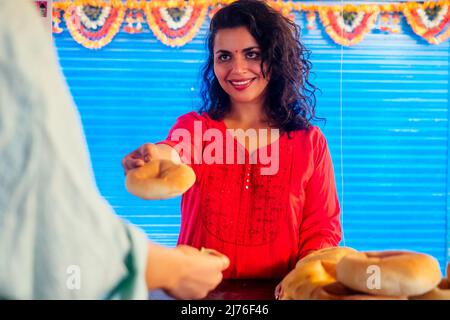 Glückliche indische Hündin salling frische traditionelle Brötchen im Basar Stockfoto