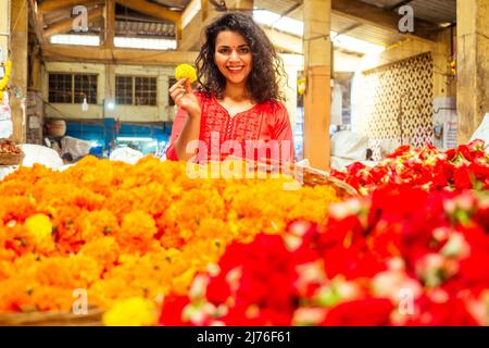 Porträt der Brünette indische Floristin weiblich in floralen Basar Blick auf die Kamera und lächeln Stockfoto
