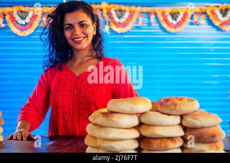 Glückliche indische Hündin salling frische traditionelle Brötchen im Basar Stockfoto