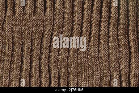 Sandfarbener, kuscheliger Strickpullover aus natürlicher Wollstruktur. Warmer blassbrauner Strickwollhintergrund. Stockfoto