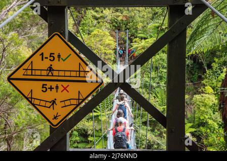 Warnschilder über eine Hängebrücke in Abel Tasman Cost Track, Neuseeland Stockfoto